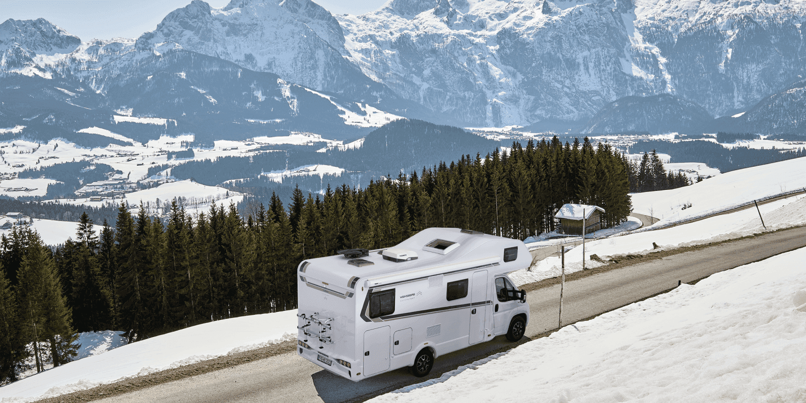 Ein Wohnmobil fährt durch eine verschneite Winterlandschaft.
